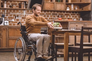 disabled man in wheelchair holding glass bowl of vegetable